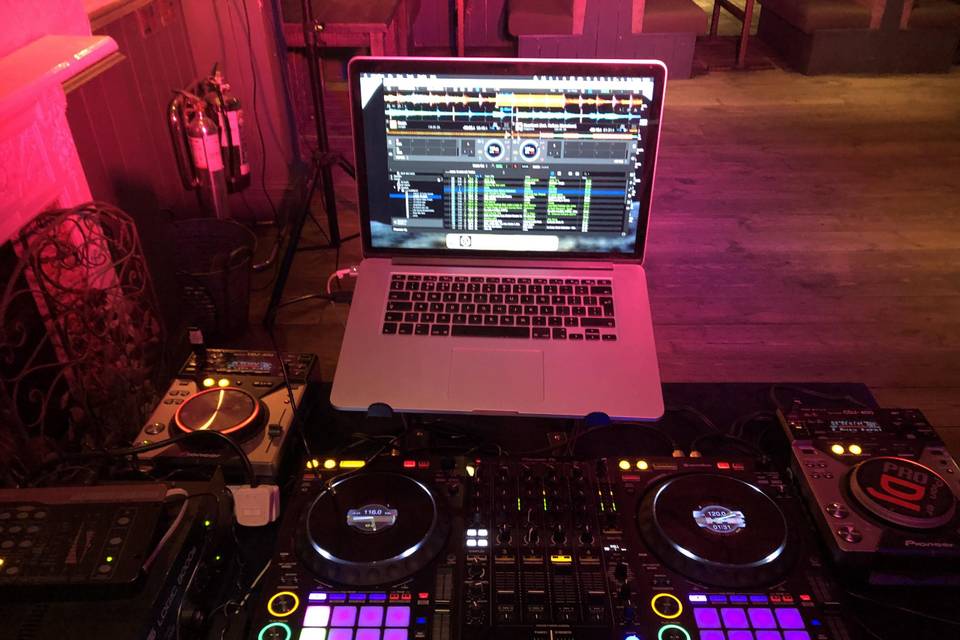 Pioneer DJ decks and laptop under red venue lighting